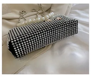 Close-up of black evening clutch bag with rhinestones, pearl handle and bead chain strap