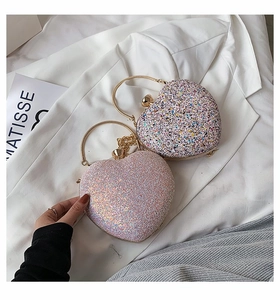 Close-up of heart-shaped glitter clutch bags with golden metal handles and chain straps