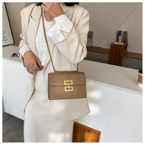 Detail of elegant brown leather bag featuring a large gold geometric lock and chain strap