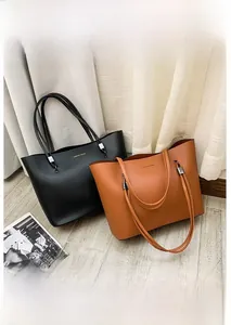 Detail of minimalist tote bags in black and brown leather with golden lettering
