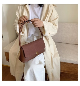 Detail of vintage brown shoulder bag with golden buckle and textured suede flap