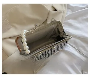 Detail view of pearl handle handbag with herringbone lining and silver metal chain strap