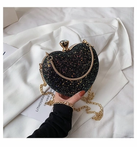 Close-up of heart-shaped evening bag with colorful sequins and golden chain strap