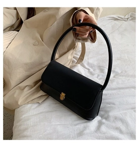 Detail of retro black leather handbag with a gold metal clasp and arc handle