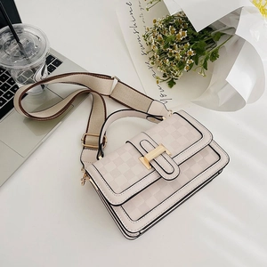 Beige checkered shoulder bag with wide strap and metallic buckle on a bright desk