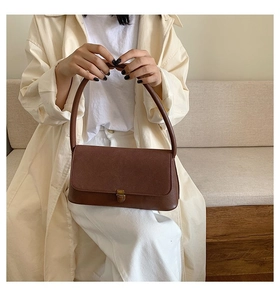 Deep brown vintage leather shoulder bag with bronze metal buckle shown in lifestyle setting
