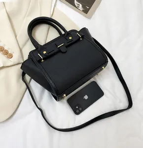 Black minimalist women's handbag shown with smartphone for size reference detail