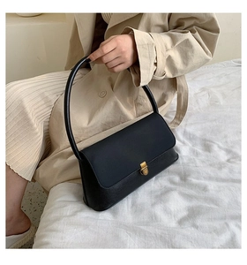 Detail of black pebbled leather shoulder bag with a gold rectangular metal buckle closure