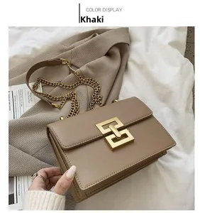 Flat lay of khaki crossbody bag with golden interlocking clasp and chain on white sheets