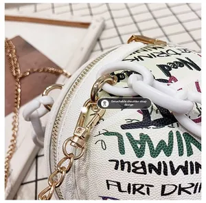 Détail de la chaîne dorée amovible et bandoulière acrylique sur le sac graffiti blanc