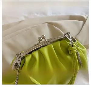 Détail d'un sac à main plissé vert vif avec fermoir argenté et nœud en cuir élégant