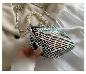 Macro side view of a luxury rhinestone shell handbag with pearl handle and silver chain strap