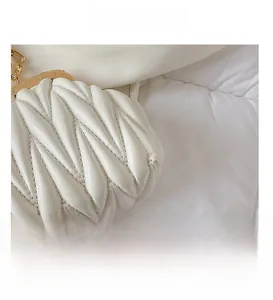 Macro shot of white pleated leather texture and golden metal clasp on women's handbag