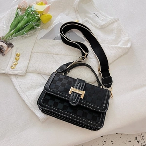 Close-up of black checkered texture handbag with gold H buckle on tweed jacket