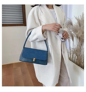 Detail of navy blue shoulder bag showing suede and leather textures with gold buckle