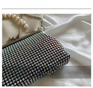 Detail of evening clutch featuring iridescent rhinestones, pearl handle, and silver chain