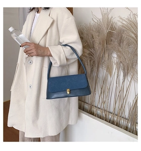 Blue suede and leather baguette bag featuring a gold rectangular metal lock detail
