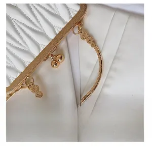 Detail of white pleated leather bag with engraved golden metal frame and round handle