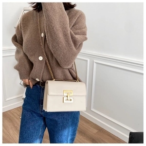 Detail of off-white leather crossbody bag with gold chain and geometric lock closure