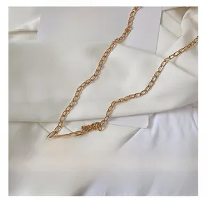 Detail presentation of flat gold metal chain strap on a stylish minimalist shoulder bag