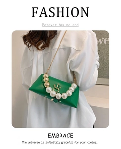 Detail of green leather handbag featuring large pearl handle and metal ring lock closure