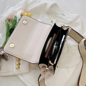 Internal view of cream small square bag showing multi-compartments and gold hardware