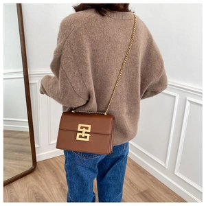 Brown rectangular leather flap bag with gold geometric lock and chain strap on a model