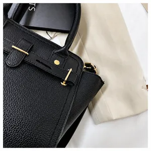Detail of black lychee grain leather handbag with gold metal clasp and rivet hardware