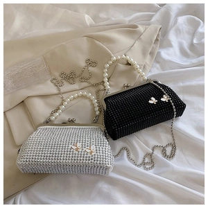 Detailed shot of two glittering rhinestone evening bags with pearl handles and butterfly decor
