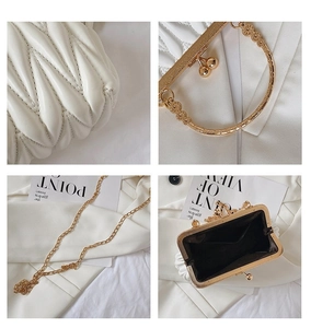 Detail view of white quilted handbag featuring gold ring handle and chain strap texture