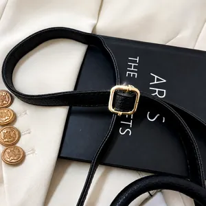 Detail of adjustable black lychee leather shoulder strap with gold-tone square buckle