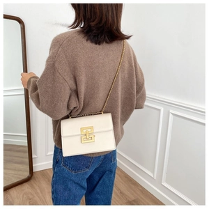 Detail of off-white lychee leather crossbody bag with golden geometric metal lock
