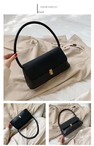 Detail of a minimalist black leather handbag with a round handle and gold metal clasp