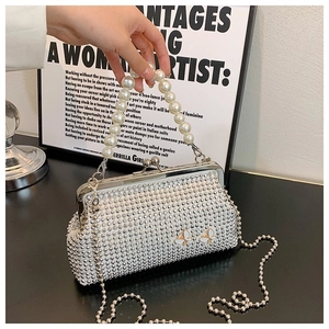Macro detail of silver handbag with pearl handle, crystal studs, and butterfly accents