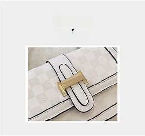 Detail of white leather shoulder bag featuring checkered embossing and a gold H buckle