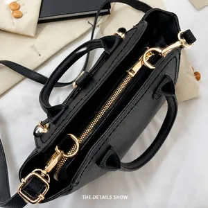 Close-up of a black lychee leather handbag showing interior space and smooth gold zipper