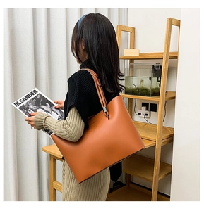 Detail of caramel leather tote bag showing large capacity and slim shoulder straps