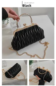 Detail of black matelassé handbag featuring golden metal handles and vintage clasp