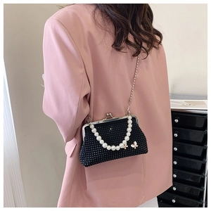 Detail of black beaded handbag with pearl handle and golden butterfly ornament