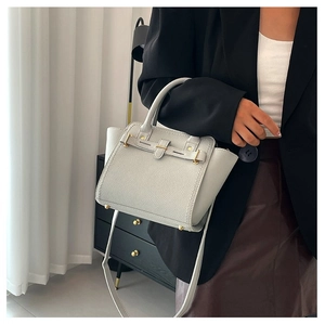 Beige lychee leather Kelly style handbag with gold hardware and a round top handle