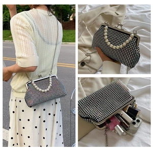 Macro detail of black rhinestone evening bag with pearl handle and metal chain strap