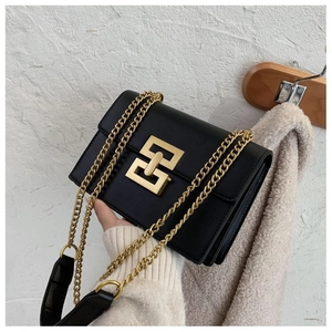 Detail of black leather crossbody bag featuring a large gold interlocking square metal clasp