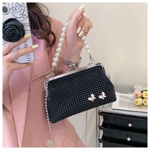 Detailed close-up of a black beaded handbag with white butterfly accents and pearl handle
