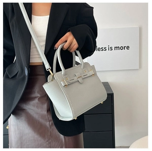 Detailed side view of light gray faux leather handbag with pebbled texture and gold hardware