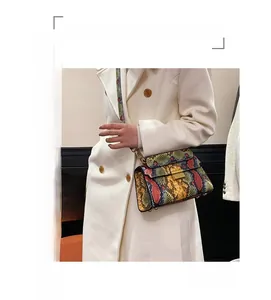 Detail of snake skin print crossbody bag with metallic buckle and woven strap
