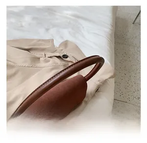 Detail of a retro brown contrast handbag with suede flap and ergonomic round handle