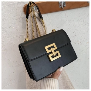 Close-up of black leather crossbody bag with gold geometric lock and chain strap