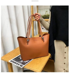 Detail view of large brown faux leather tote bag with long handles and brand logo