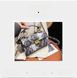 Detail of snake print crossbody bag featuring gold round metal handle and square buckle