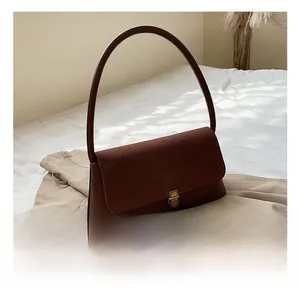 Detail of dark brown leather underarm bag with gold metal clasp and suede patchwork texture